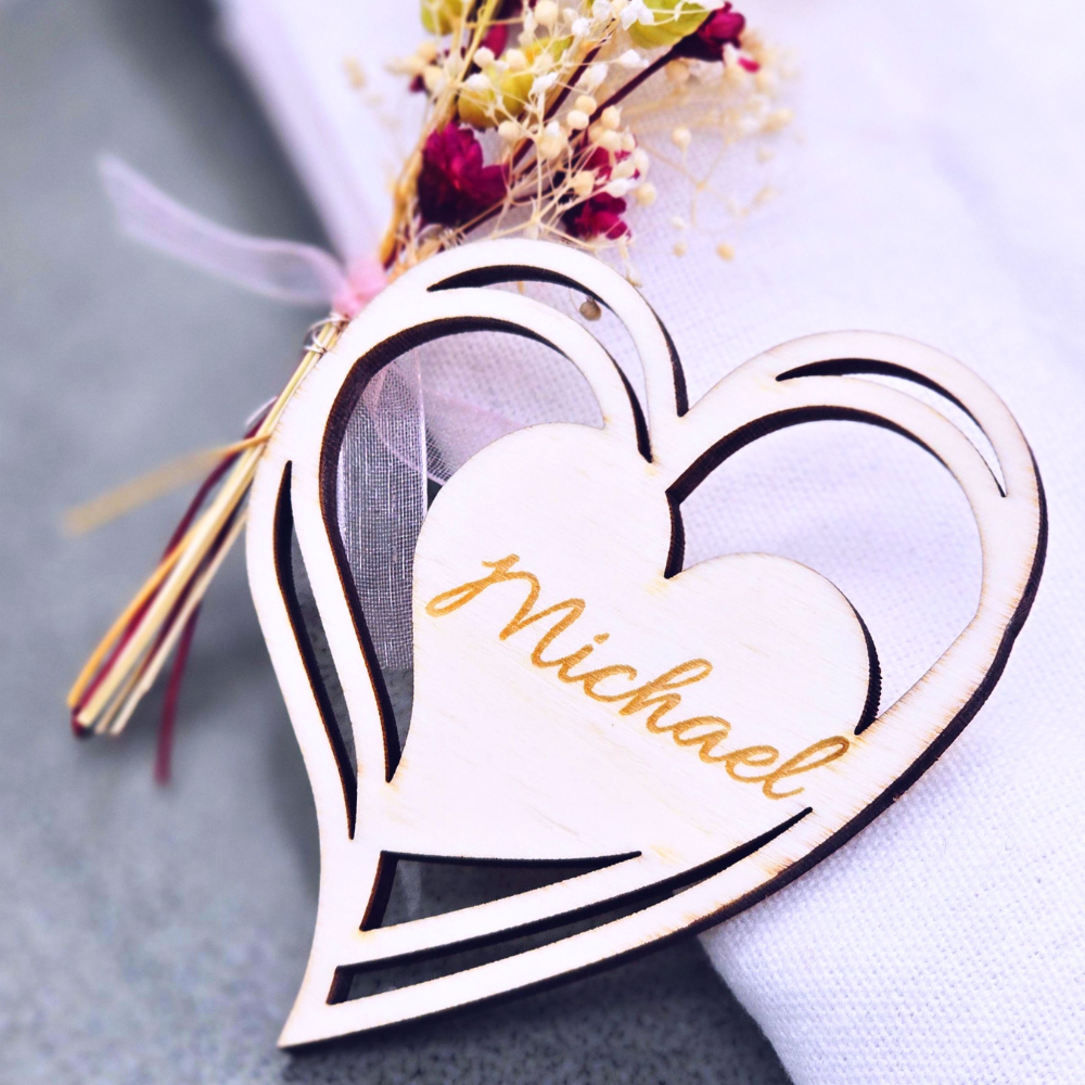 Kreatives Gastgeschenk zur Hochzeit: personalisierte Tischkarte aus Holz in Herzform mit hochwertiger Lasergravur. Als liebevolles Detail auf dem gedeckten Tisch platziert, kombiniert es dekorative Eleganz mit persönlicher Wertschätzung – ein nachhaltiges Andenken für deine Gäste.